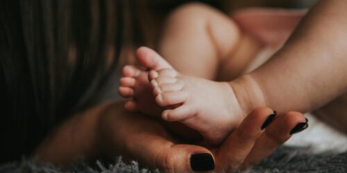 person holding baby s feet in selective focus photography