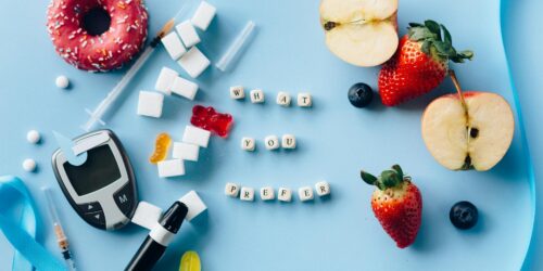 letter dices between fresh fruits and diabetes equipment on a blue surface